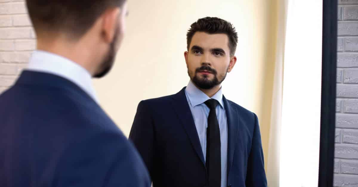 An image of a business man looking in the mirror used for blog "Letting Go of Imposter Syndrome to Strengthen Your Career" by TalentSpark